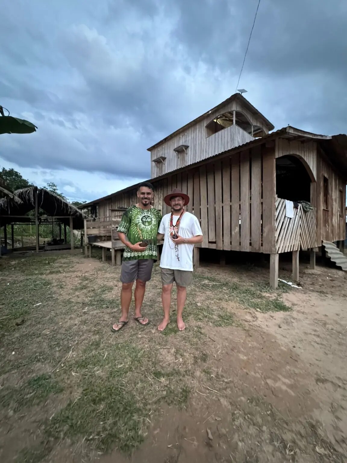 Bruno Luz e Michael Pereira diante de construção de madeira na Aldeia Chico Curumim